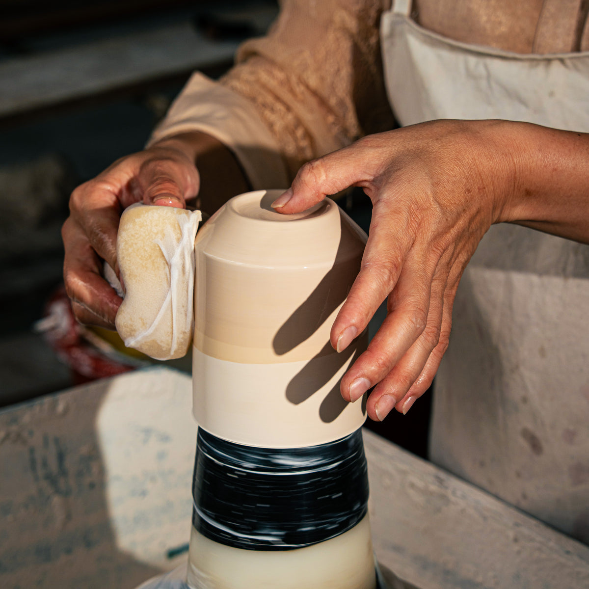 Placeholder editorial photograph of a maker finishing a ceramic vessel